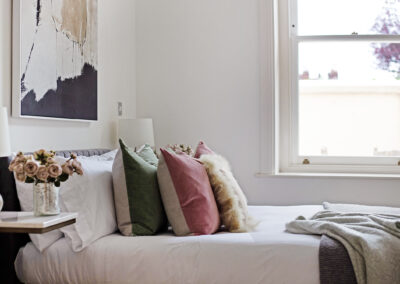 Bedroom staging by Beau property, showcasing bed with pink, green and fluffy pillows.
