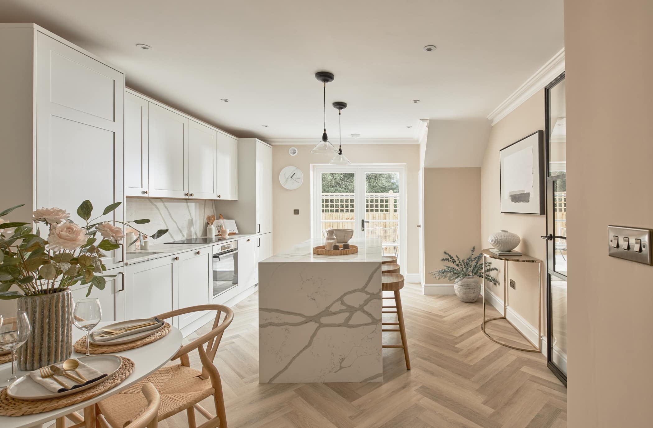 Staged home kitchen in Tunbridge Wells. Kitchen island in focus with decorative ornaments, minimalist style. Light and airy feel with gold and dark accents. Several plants thoughtfully placed to add a welcoming, fresh and homely feel.